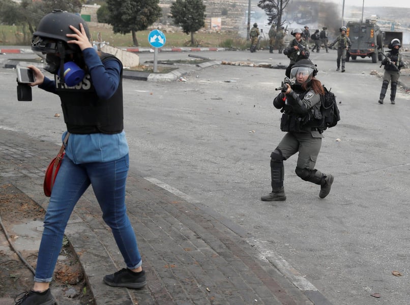 International journalists wait with cameras and press vests at a checkpoint seeking access to Gaza