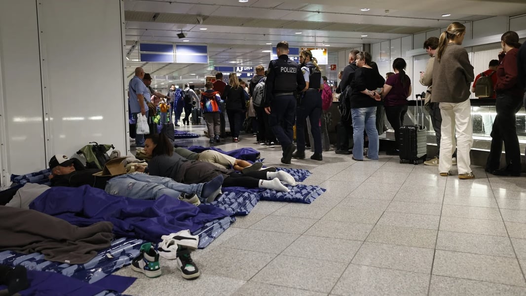 Passengers check departure boards at Munich airport after drone sightings paused operations