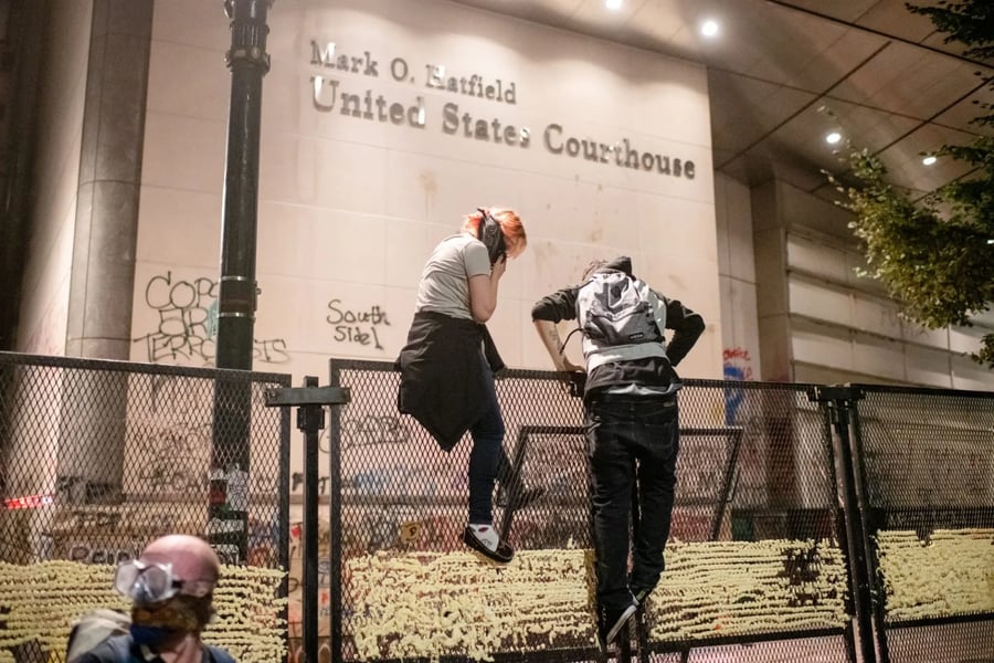 Protesters gather near fencing outside the federal courthouse in Portland