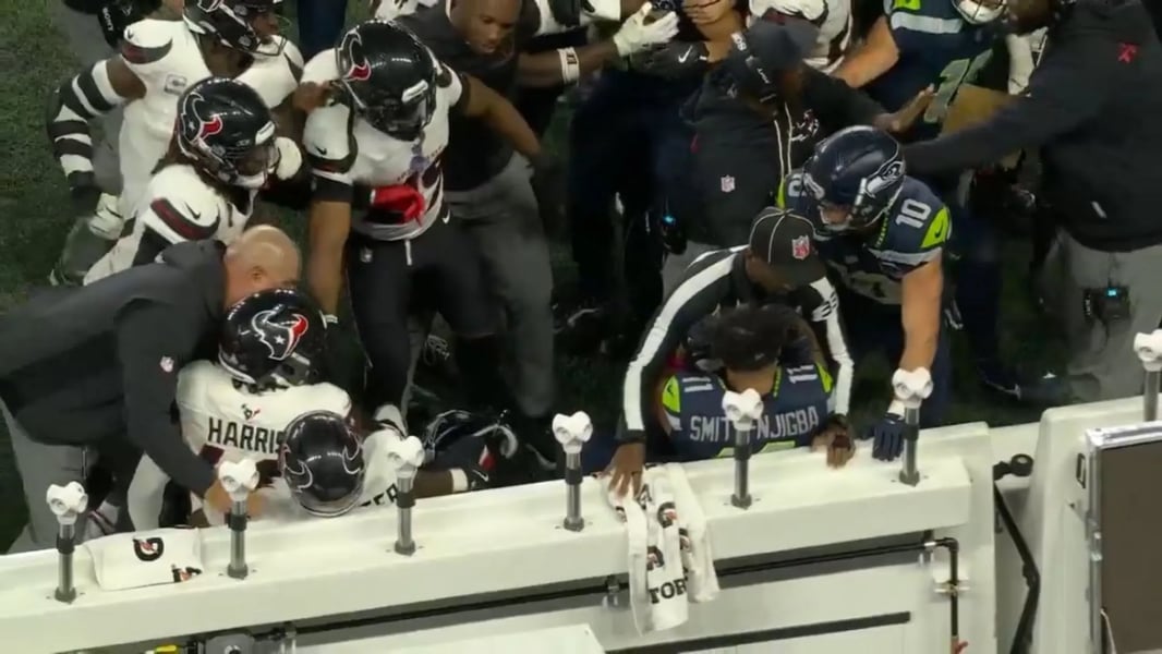 Referee Nate Jones steps between Texans players and Jaxon Smith-Njigba during the sideline scrum