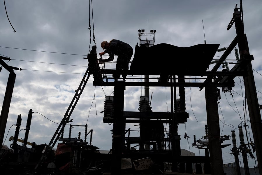 Utility workers on a transformer platform in Kyiv repair infrastructure damaged by strikes