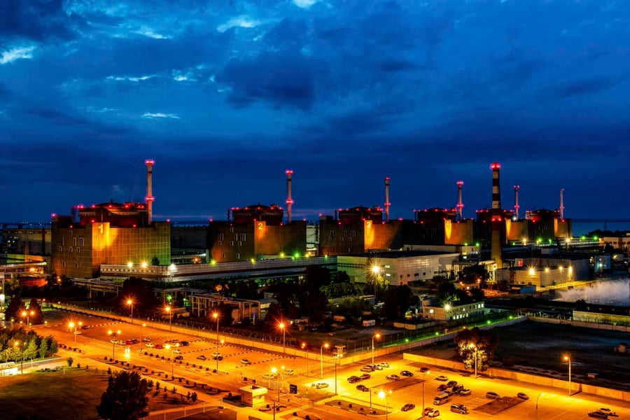 Zaporizhzhia nuclear power plant at dusk with cooling stacks and lights along the Dnieper