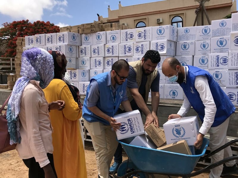 Humanitarian workers distributing food and water in refugee camp near El Fasher