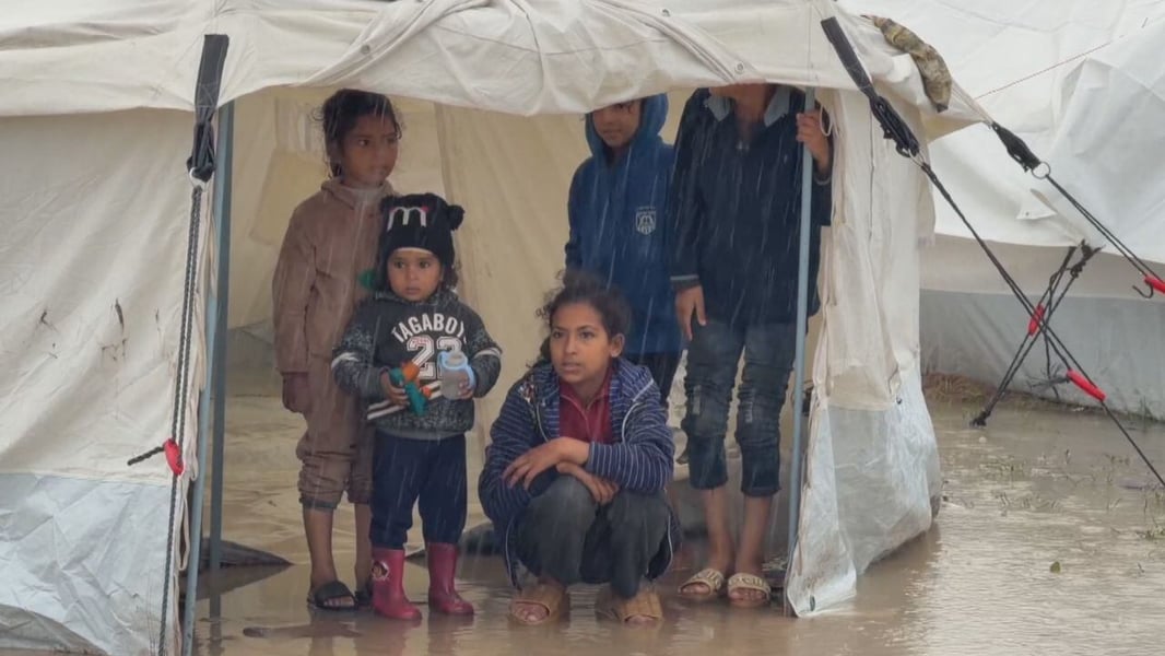 Palestinian child stands in a soaked tent after Storm Byron in Gaza.
