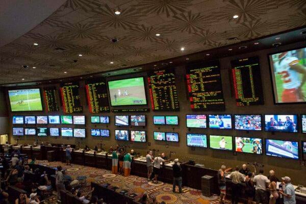 Kansas City sportsbook opening with patrons betting and large screens"