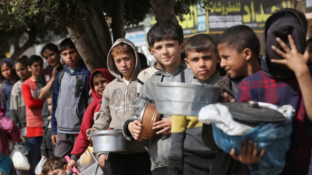 Palestinians including children queue for bread amid severe flour shortages in Gaza during ongoing war crisis