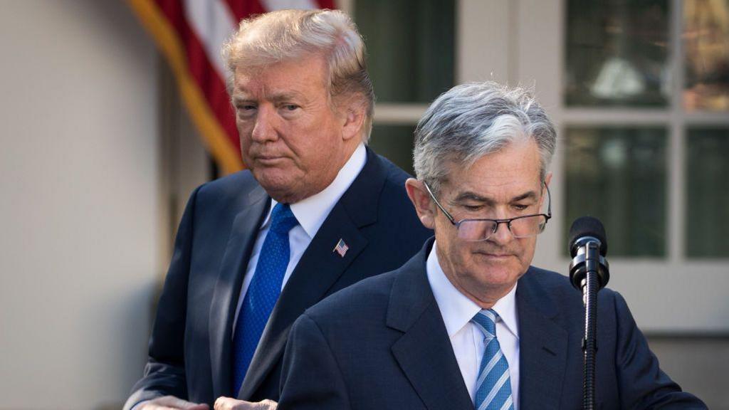 Federal Reserve Chair Jerome Powell speaks at a podium with a stern expression as he discusses the DOJ investigation into his leadership.