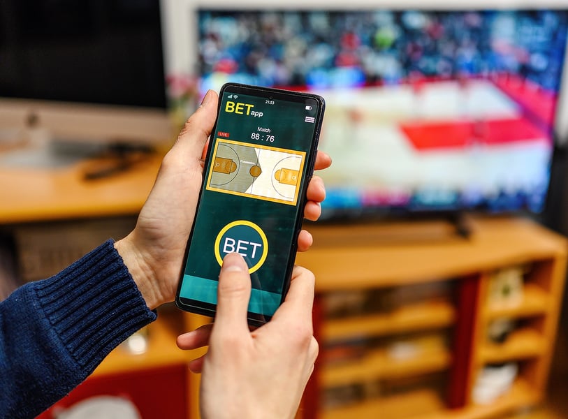 Man using smartphone for online sports betting amid rising gambling addiction crisis in Ohio