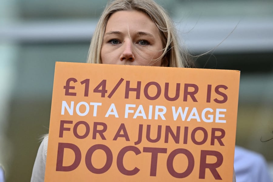Female doctor holding protest placard during UK NHS strike over pay and training cuts