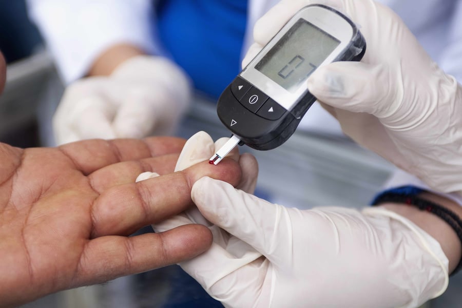 Doctor performing a finger-prick blood glucose test on a patient in Wales