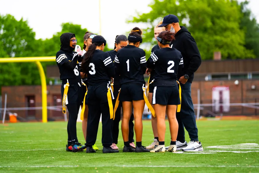 College women’s flag football team gathers during a game