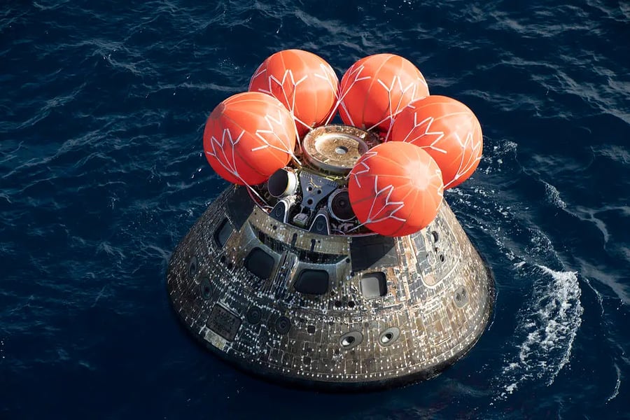 Orion spacecraft floating in the Pacific Ocean after Artemis II lunar mission splashdown with NASA recovery teams nearby
