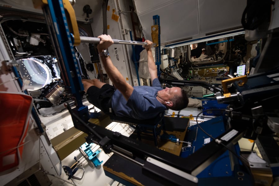 NASA astronaut Bob Hines exercising on the Advanced Resistive Exercise Device ARED inside the International Space Station, the kind of bulky current-generation gym equipment HIFIm aims to replace