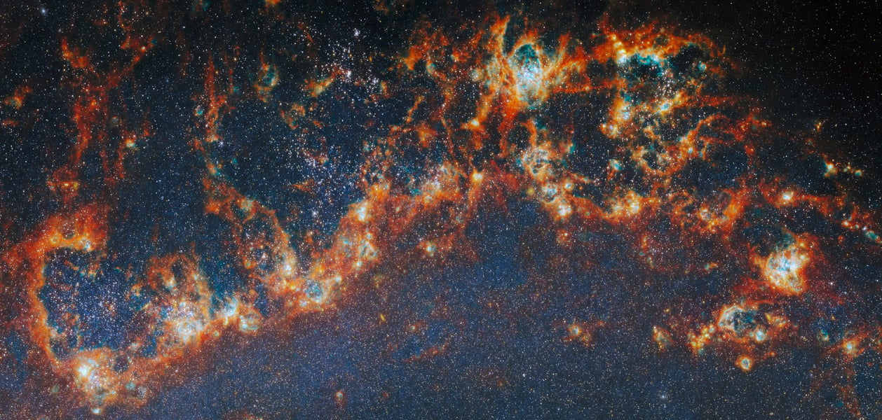 Webb Telescope near-infrared image showing Messier 51 spiral arm with young star clusters lighting bubbles inside dense gas