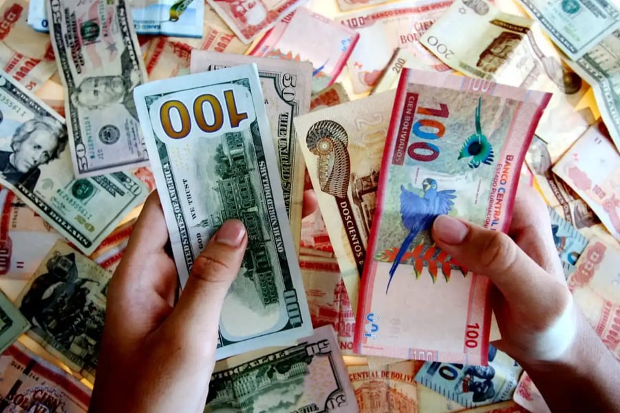Bolivian banknotes and US dollars on a table in La Paz as Bolivia abandons its 15-year dollar peg and moves to a flexible exchange rate