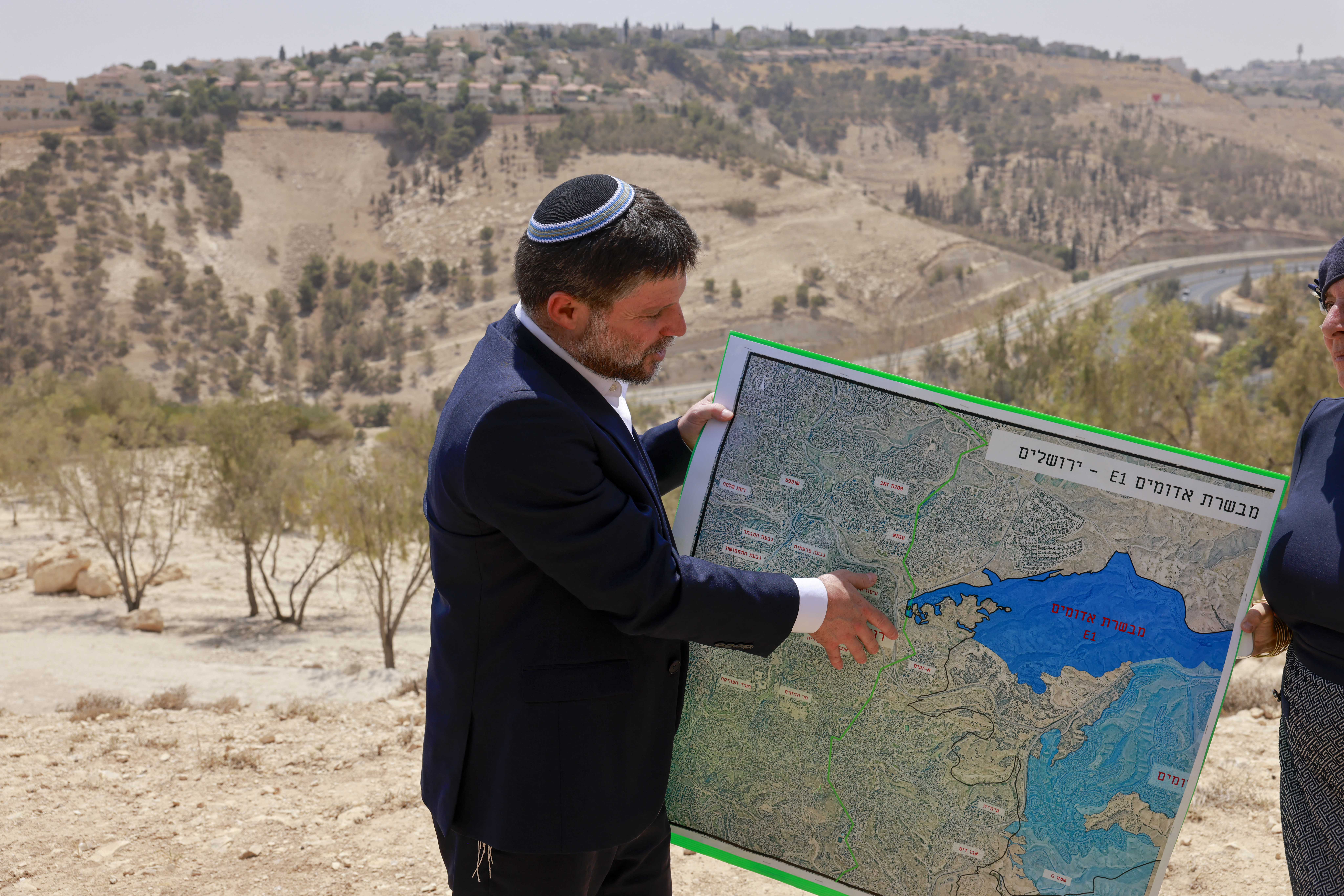 Israeli Finance Minister Bezalel Smotrich holds a map of the E1 settlement project at a press conference near Maale Adumim in the West Bank, August 2025