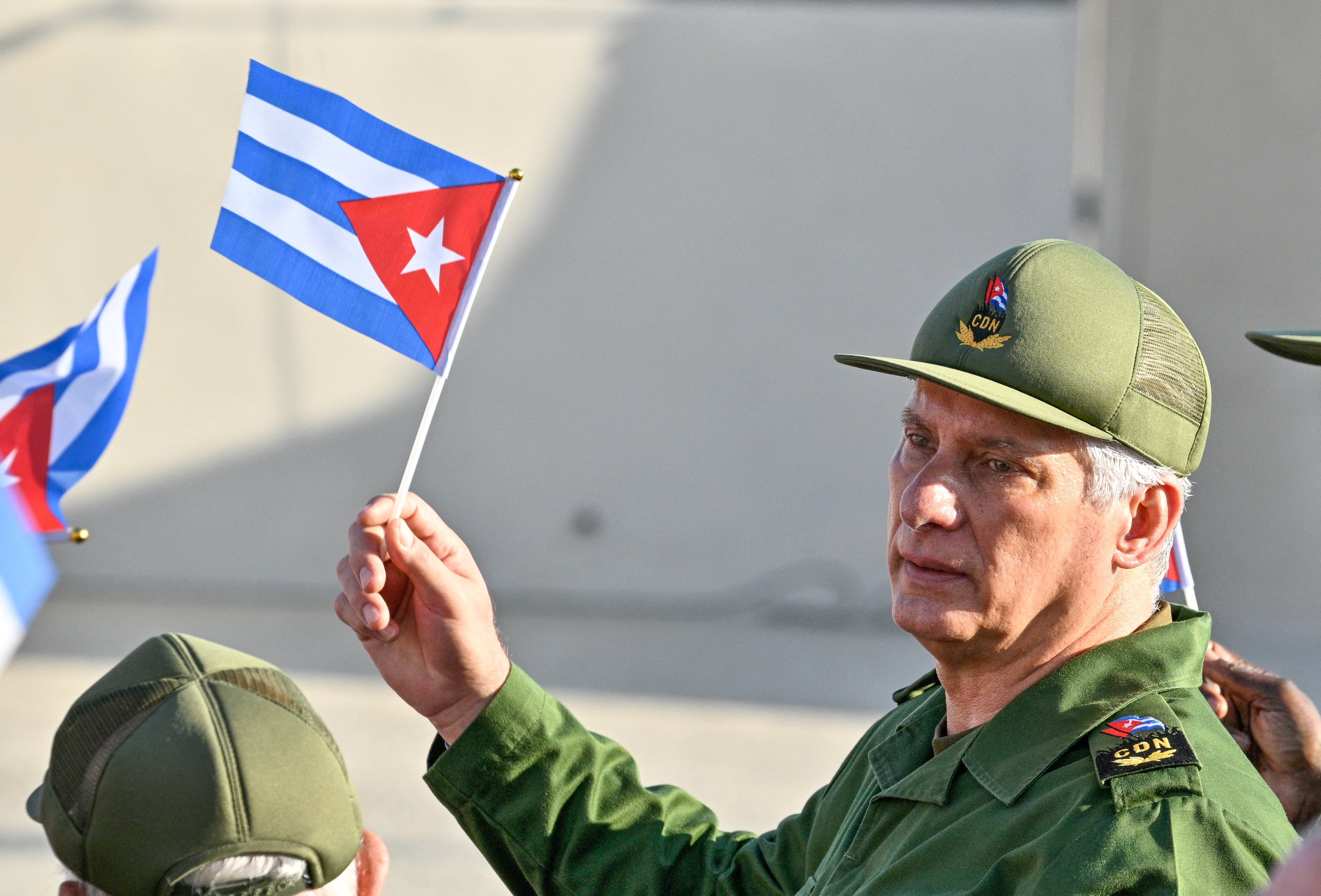 Cuban President Miguel Diaz-Canel holds Cuban flag at rally amid US blockade