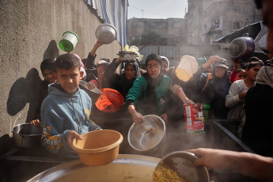 Palestinian women queue to receive food donations at a community kitchen in Nuseirat Gaza