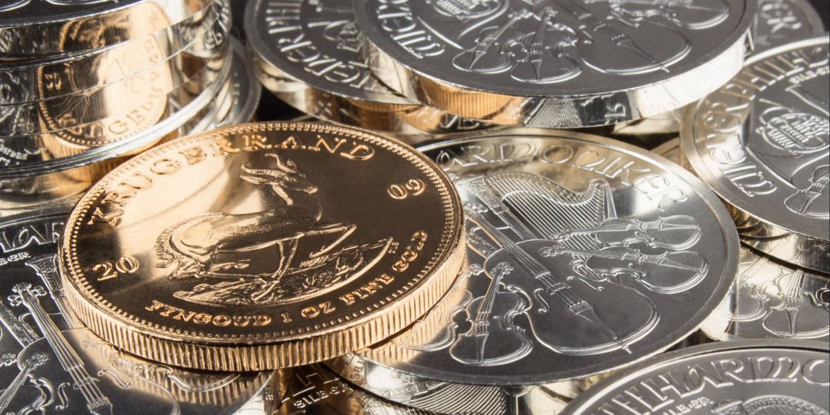Gold Krugerrand coin atop silver coins representing precious metals market losses during Iran-Israel war