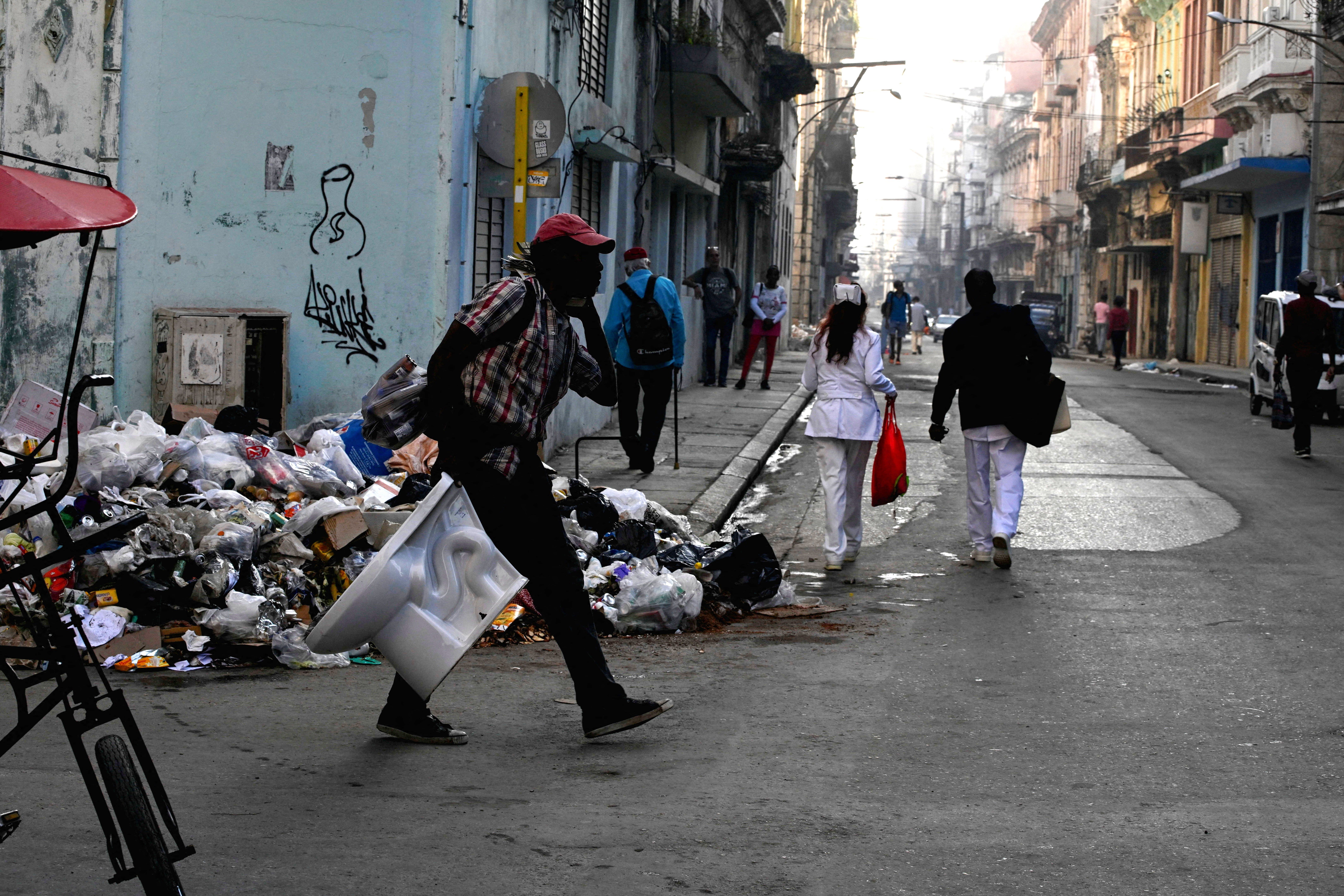 People walk past trash on a street in downtown Havana Cuba as US oil embargo triggers fuel shortages and crisis in 2026