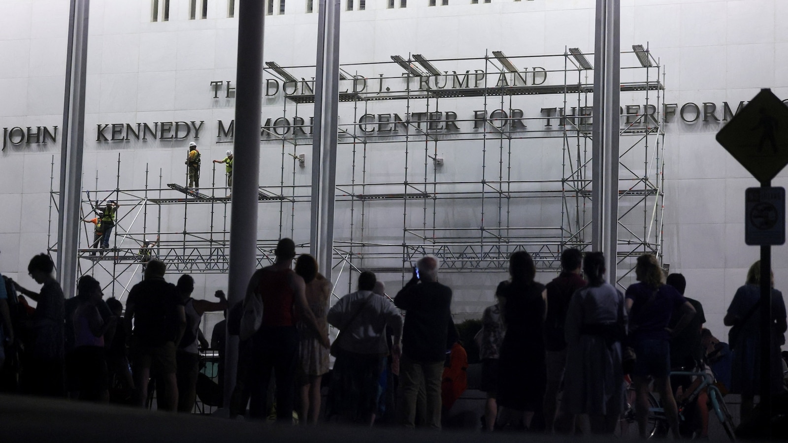 Workers on scaffolding remove lettering of Donald Trump's name from the Kennedy Center facade