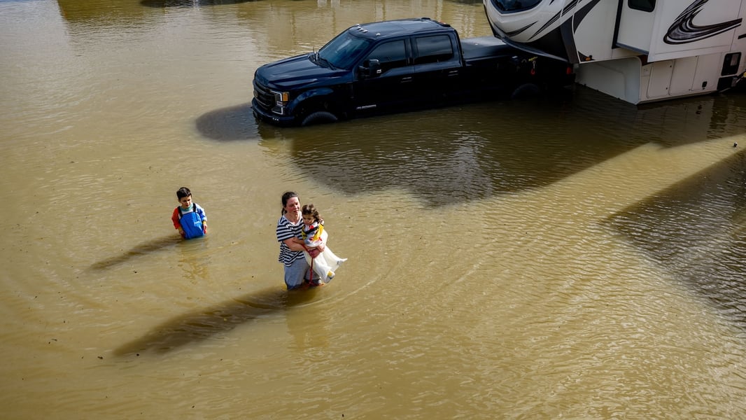 People wade through a recreational vehicle park flooded by a king tide near Corte Madera in Marin County, California