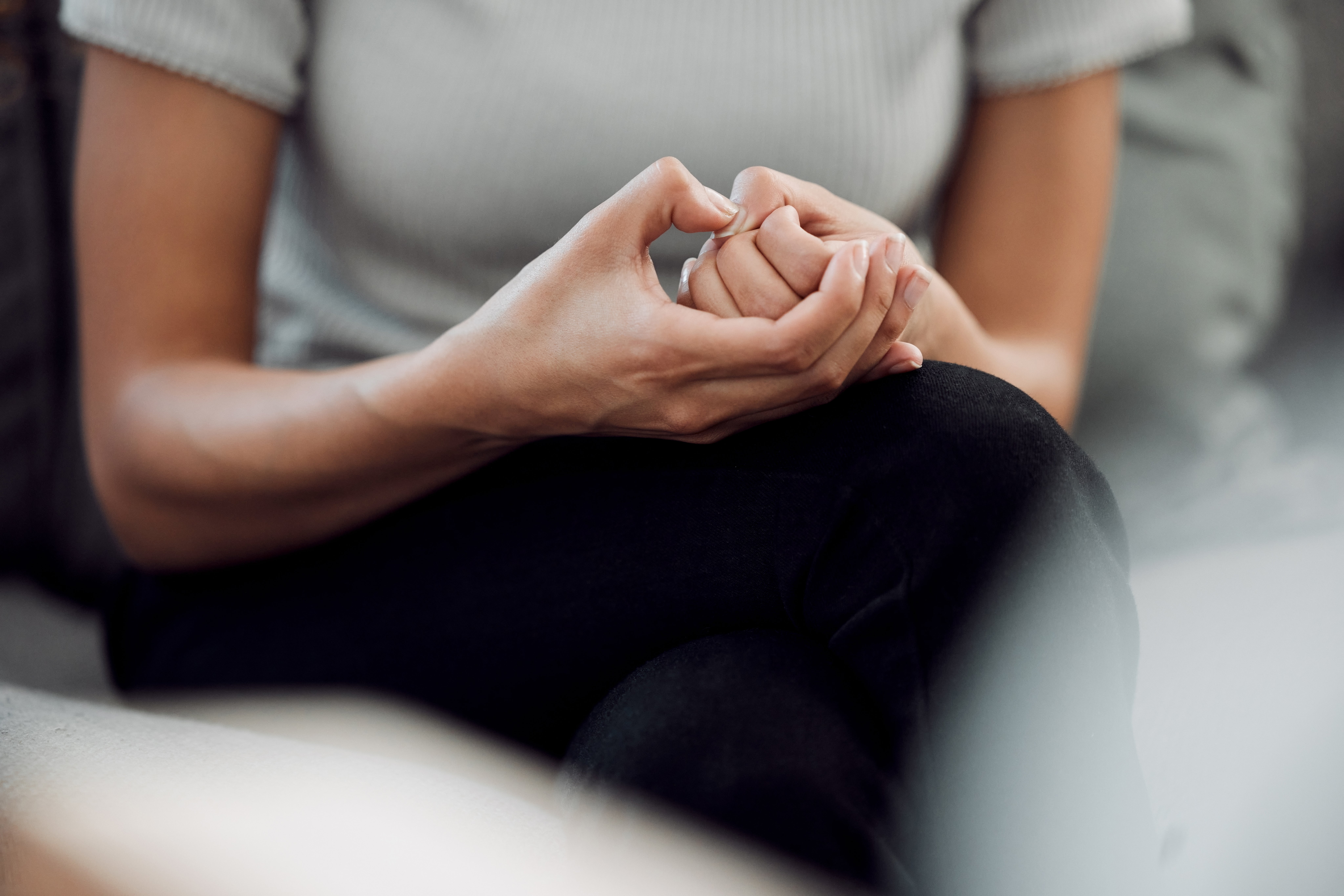 Person sitting with hands clasped, appearing thoughtful or anxious, representing the distress caused by moral OCD