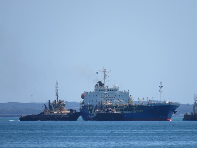 Oil and chemical tanker moored at a refinery jetty, illustrating the crude shipments repriced by the US-Iran exchange near Hormuz