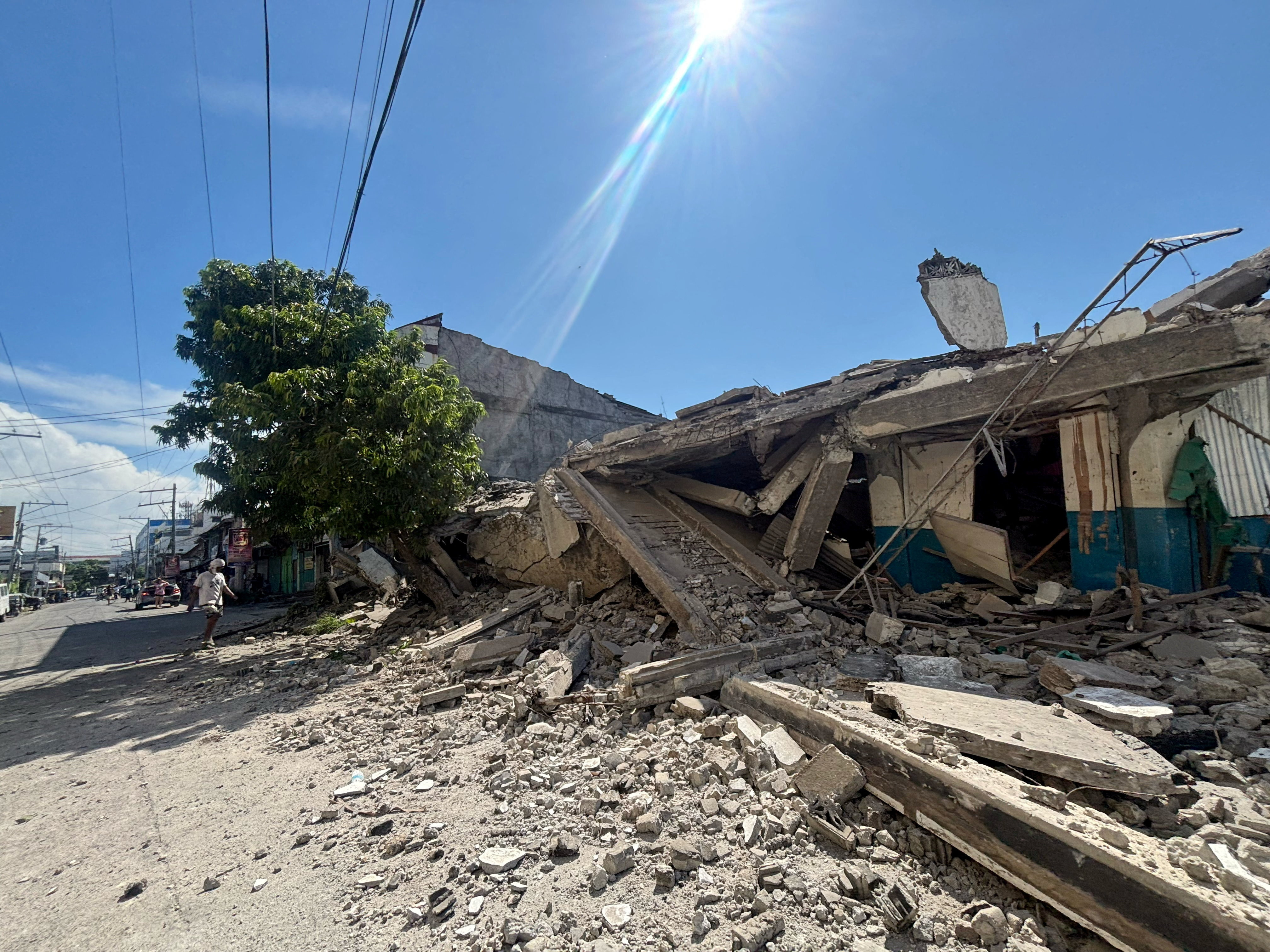 A man walks near a collapsed building after the magnitude 7.8 earthquake in General Santos, Mindanao