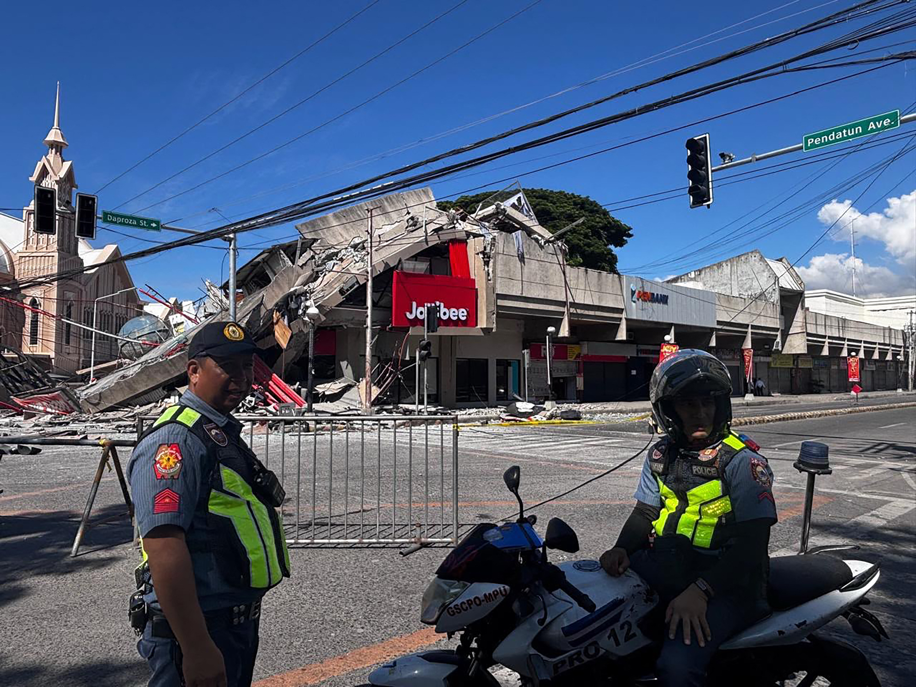 Police gather in front of a collapsed building after a magnitude 7.8 earthquake in General Santos, Philippines