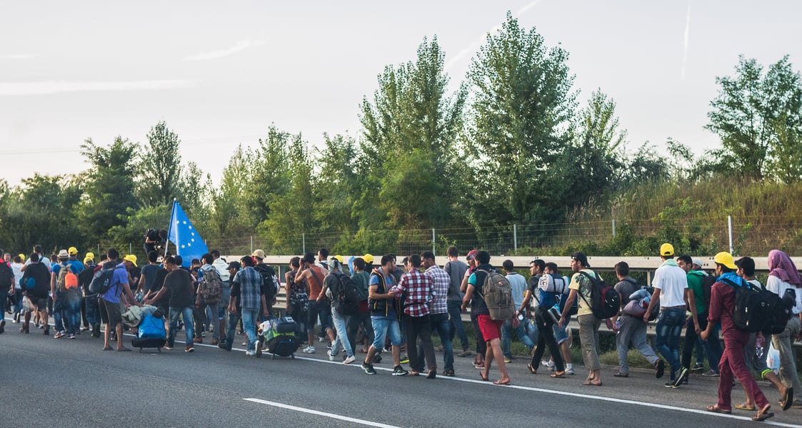 Refugees marching along a road in Europe, the population the EU Migration and Asylum Pact governs