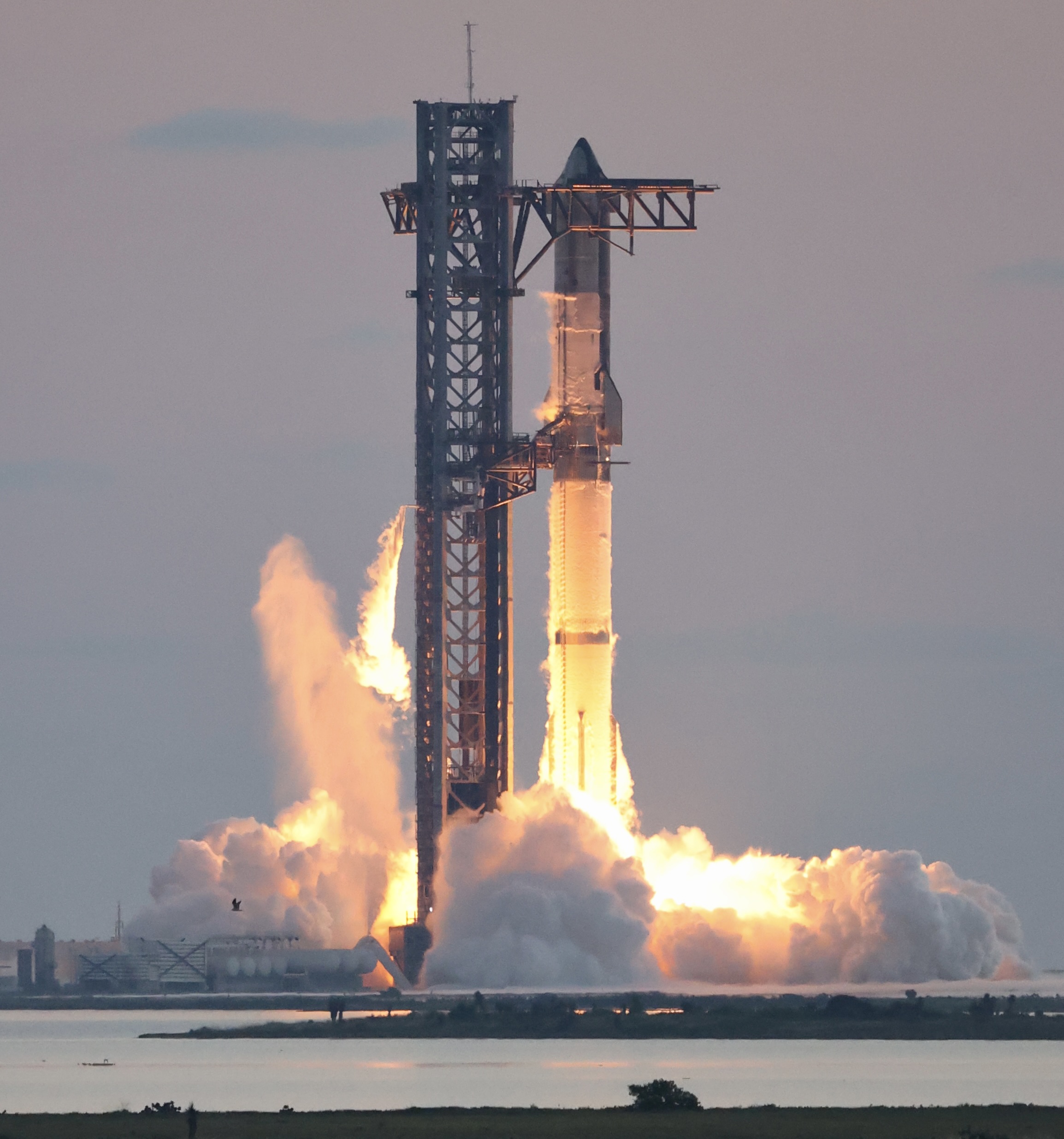 SpaceX's Starship rocket igniting its engines at liftoff in a cloud of flame and exhaust