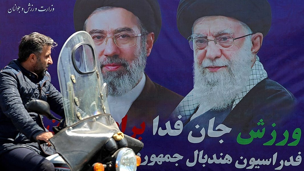 A motorist passes a banner depicting the late Ali Khamenei in Tehran ahead of the US-Iran memorandum signing