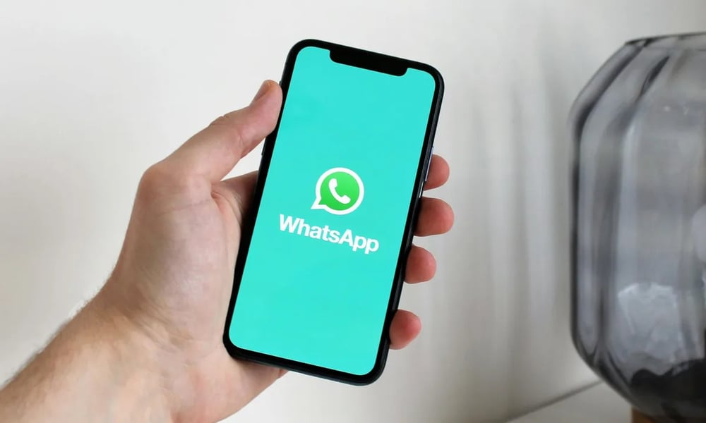WhatsApp iOS update showing scheduled messages, view once texts, and disappearing chat features on smartphone screen
