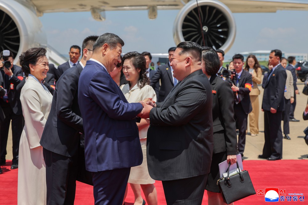 Kim Jong Un greeting Xi Jinping on his arrival at Pyongyang's Sunan airport in June 2026