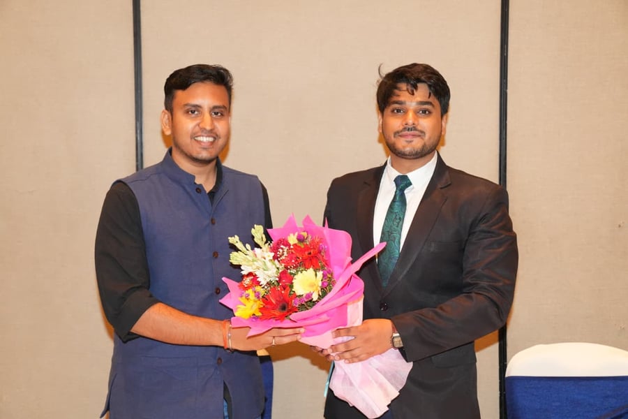 Two men in formal attire presenting a document at the Visvaniti Foundation 1st Annual Meeting in New Delhi