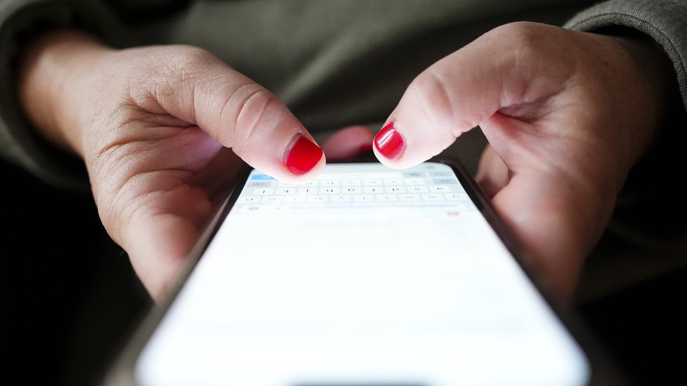 A person's hands typing on a smartphone, illustrating the Canadian wireless fee dispute