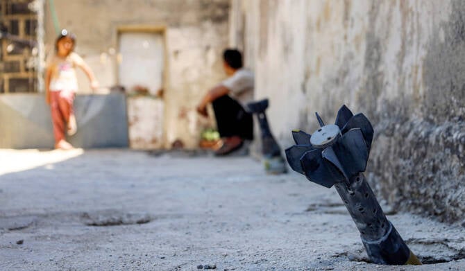 A man and child near unexploded artillery shell from Israeli bombardment in Syria Daraa province near Golan Heights June 2026