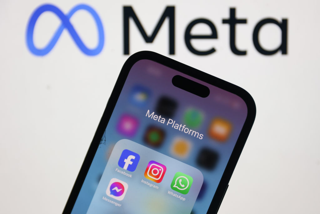 Meta logo on laptop screen with Facebook Instagram WhatsApp and Messenger icons on phone screen