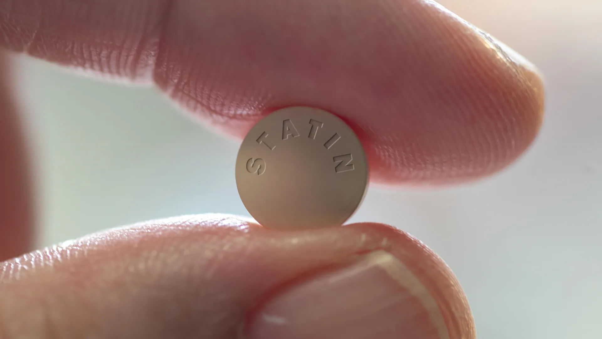 Person holding a statin pill close up for Oxford muscle risk study