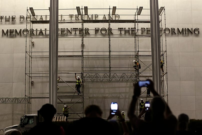 Workers install signage during Trump administration airport renaming in Florida