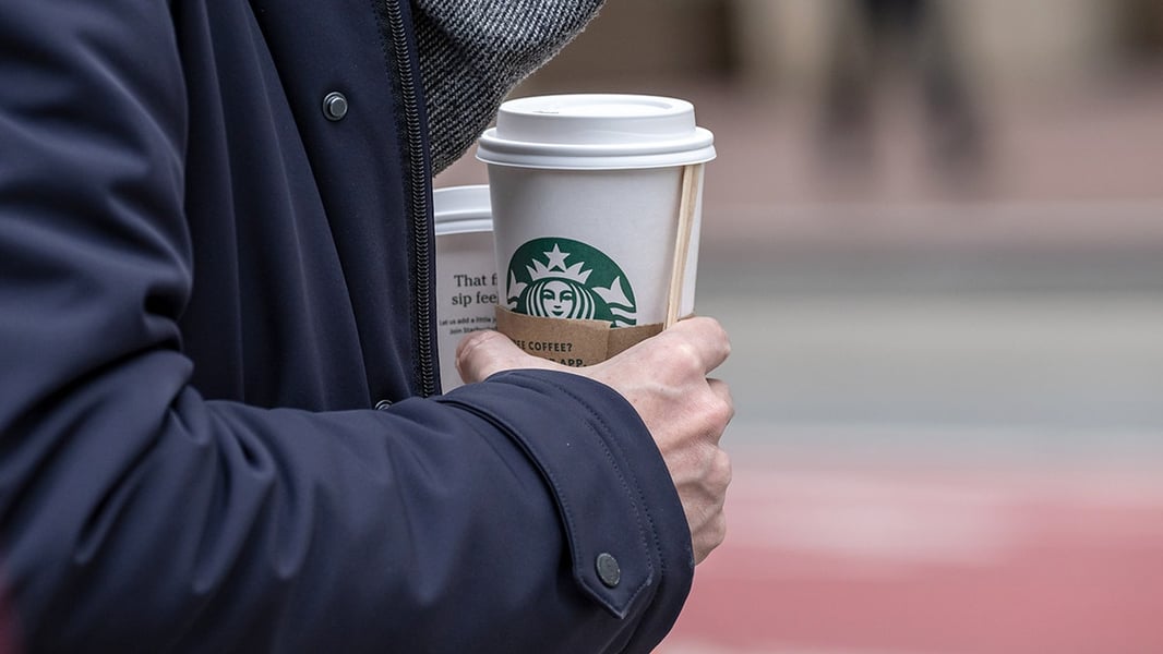 A customer holds a Starbucks coffee cup, reflecting the chain's improving customer traffic under CEO Brian Niccol's Back to Starbucks strategy