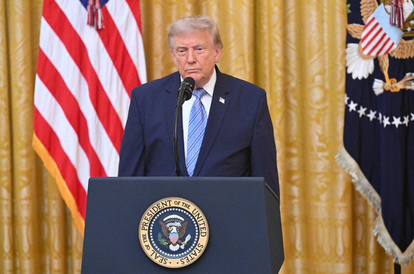 President Donald Trump at a lectern with US flag, threatening Canada with higher tariffs over wildfire smoke