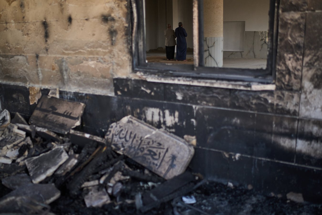 Palestinian worshippers praying inside a mosque damaged by arson attack in the West Bank