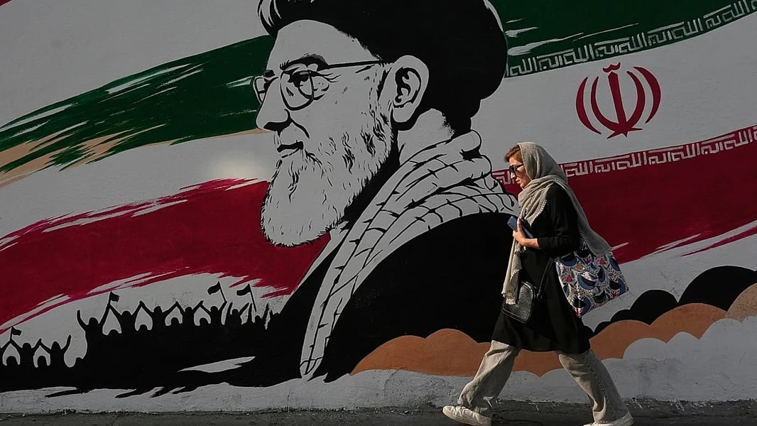 A woman walks past a large mural of the late Iranian Supreme Leader Ayatollah Ali Khamenei on Azadi (Freedom) Street in Tehran, July 2026
