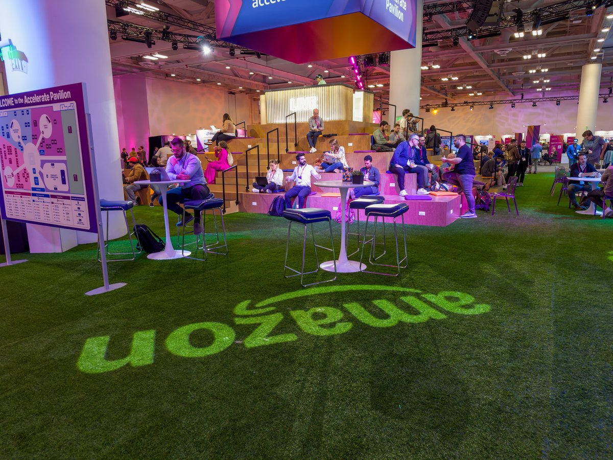 Attendees networking at the Amazon Accelerate conference innovation expo with Amazon branding visible in the background