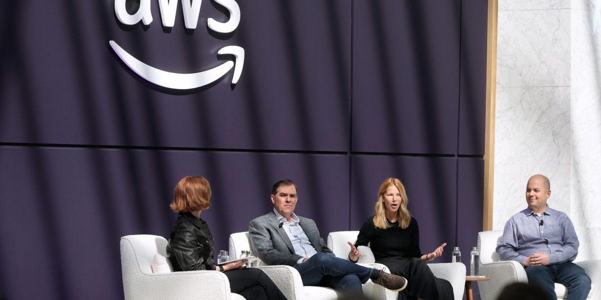AMZN stock today: executives on stage beneath the Amazon Web Services logo, the division driving Amazon's AI infrastructure spending