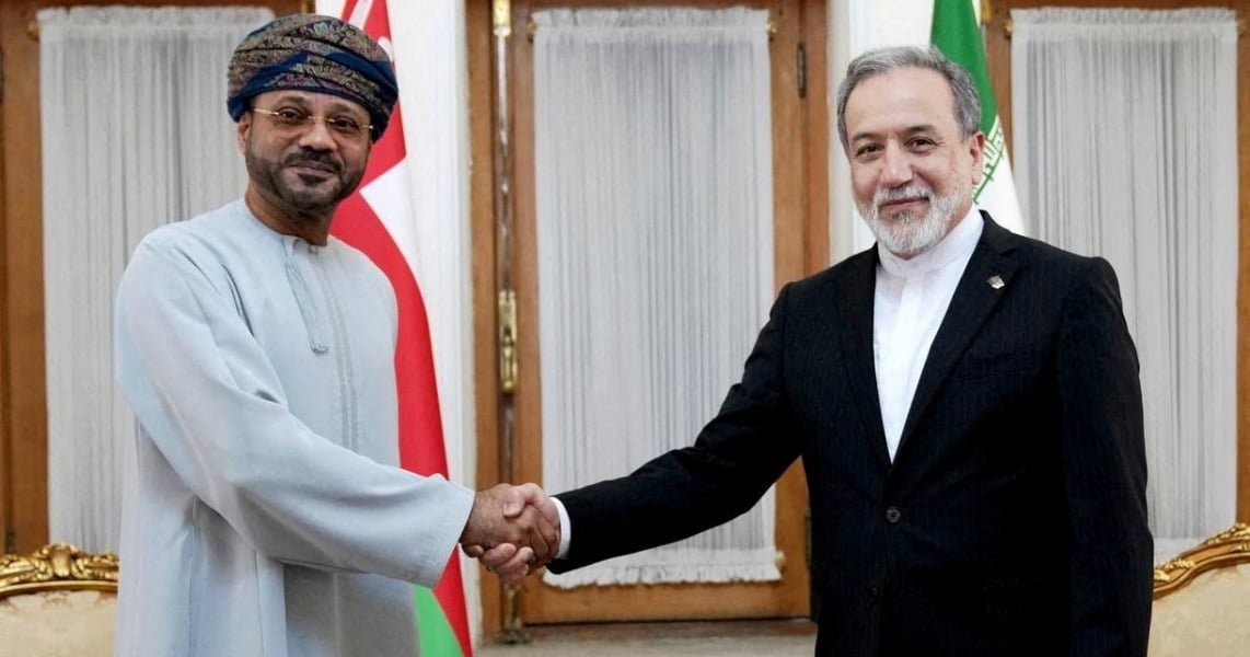 Abbas Araghchi shakes hands with Oman's foreign minister in front of Iranian and Omani flags