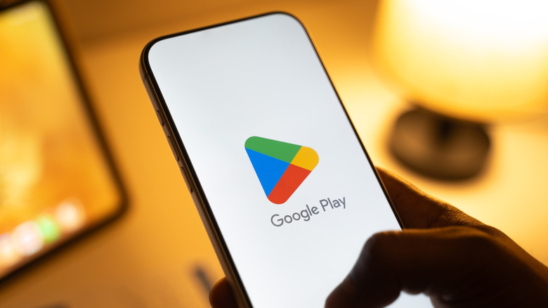 Person holding a phone displaying the Google Play Store logo