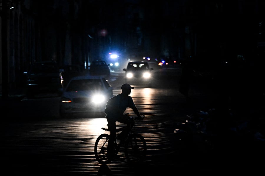 A man rides a bicycle down a darkened street during a blackout in Havana, Cuba
